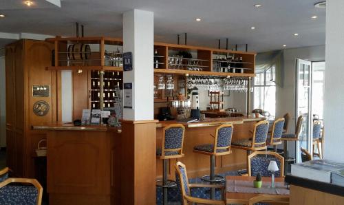 ein Restaurant mit einer Bar mit Stühlen drum herum in der Unterkunft Hotel Garni Meeresblick in Glowe