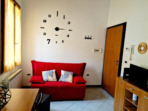 ein rotes Sofa im Wohnzimmer mit einer Uhr an der Wand in der Unterkunft Appartamento IN CENTRO Free Wi-Fi, Self check-in in Forlì