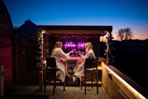 two women sitting at a table on a patio at night at Tan Y Bryn Glamping in Conwy
