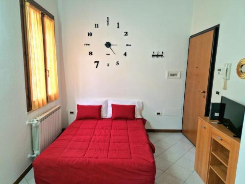 ein Schlafzimmer mit einem roten Bett mit einer Uhr an der Wand in der Unterkunft Appartamento IN CENTRO Free Wi-Fi, Self check-in in Forlì