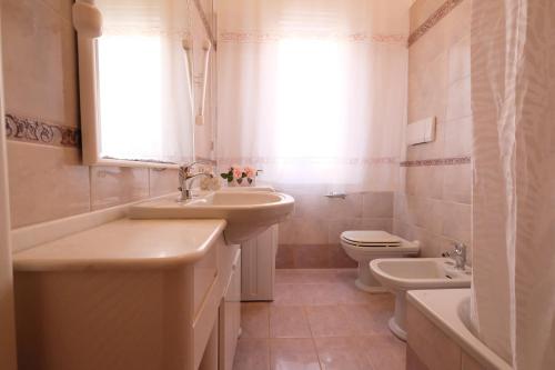 Un baño con dos lavabos y un inodoro y una ventana. en Orchidea PT - Pineto Vacanza, en Pineto
