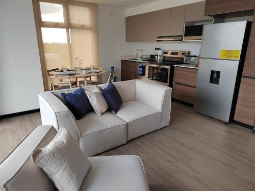 a living room with a white couch and a kitchen at Hermoso apartamento nuevo en zona 10! in Guatemala