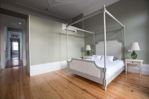 a bedroom with a canopy bed and a wooden floor at Porto Vintage Guesthouse in Porto