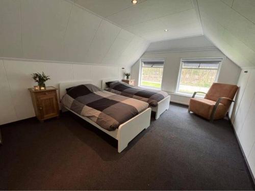 a attic bedroom with two beds and a chair at ‘t Bosrandje in Odoorn