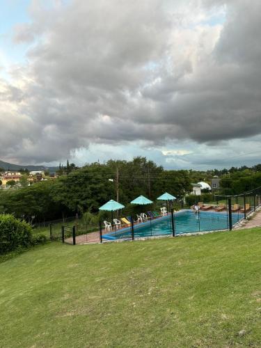 a swimming pool with umbrellas and people in the water at Castelar - Hotel & Apart in Huerta Grande