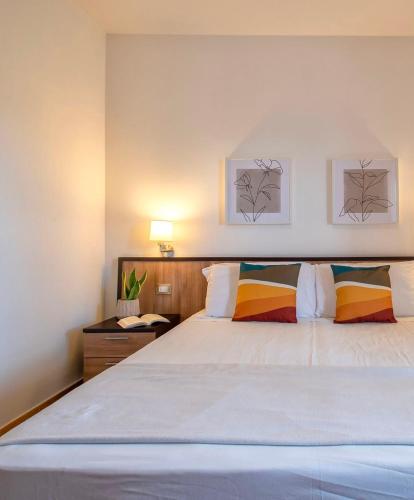 a bedroom with a large white bed with colorful pillows at LE TERRAZZE apartments in Alghero