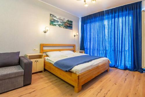1 dormitorio con cama, sofá y cortinas azules en Room310, en Gudauri