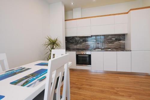 a kitchen with white cabinets and a table and chairs at JD Luxury Apartments in Vlorë