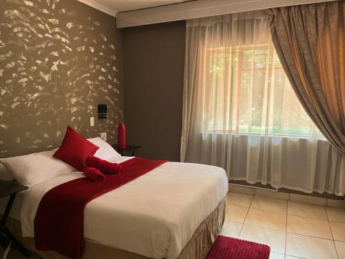 a bedroom with a bed with red pillows and a window at Angelmalatji guesthouse in Graskop