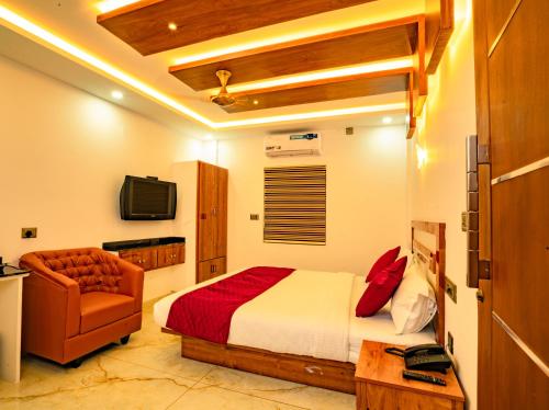 una camera con letto, sedia e televisore di MARINA SUITES AIRPORT HOTEL a Cochin