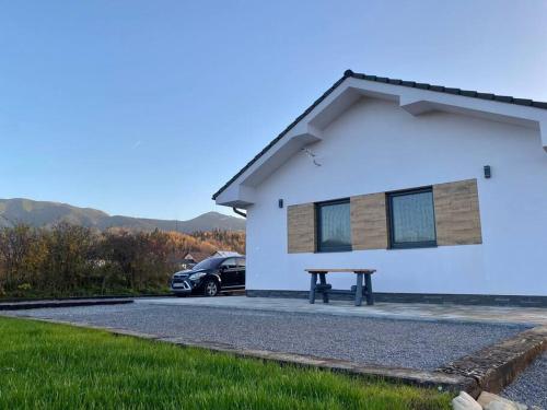a car parked next to a white building with a picnic table at Chata North Point Zuberec pod Roháčmi in Zuberec
