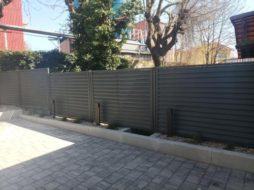 a fence in front of a building with trees at Sileo Apart No.85 in Ustka