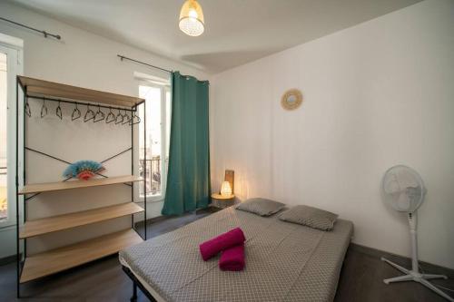 a bedroom with a bed with pink pillows and a fan at Appartement tout équipé à coté/Vieux port/Noailles in Marseille
