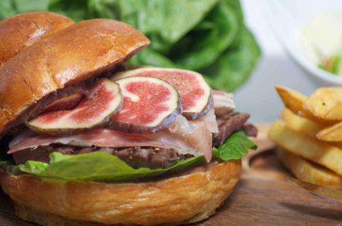 a sandwich with meat and vegetables on a bun with fries at Hotel Westfalen Hof in Rahden