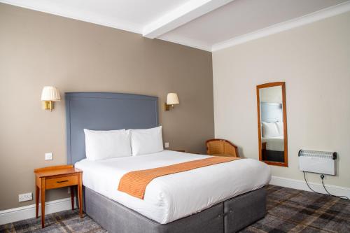 a hotel room with a large bed and a mirror at Arnos Manor Hotel in Bristol