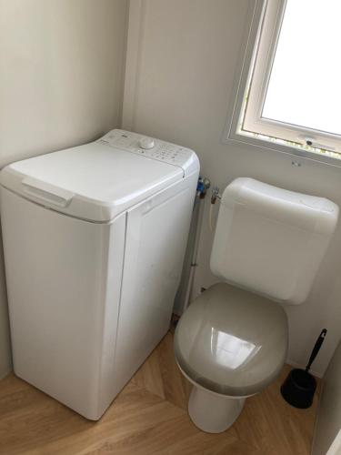 a bathroom with a white toilet and a window at Mobil home 3 chambres mar estang 4 étoiles ! in Canet-en-Roussillon