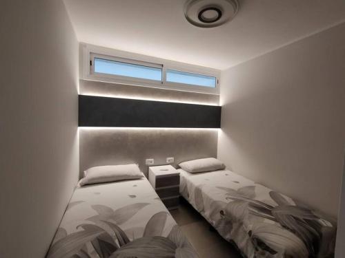 twee bedden in een kleine kamer met een raam bij Holiday Apartment Alegranza in Playa del Inglés