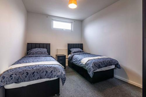 a bedroom with two beds and a window at Luxury stay in EastwoodTown centre in Eastwood