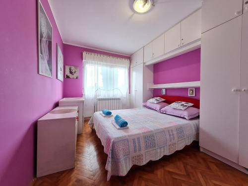 - une chambre avec des murs violets et un grand lit dans l'établissement Ksenija, à Novi Vinodolski