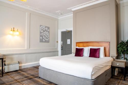 a bedroom with a large white bed with red pillows at Arnos Manor Hotel in Bristol