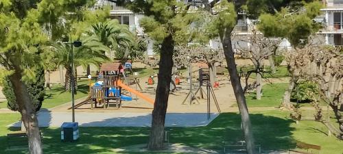 un parque con parque infantil con tobogán y árboles en Reus y MAr Salou, en Salou