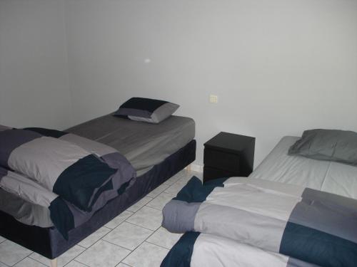 a bedroom with two beds and a tiled floor at appartement Courcelles in Courcelles