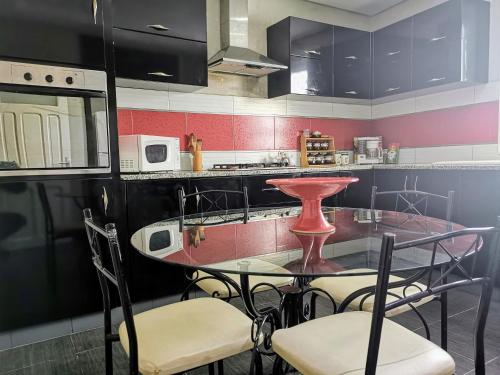 una cocina con mesa de cristal y sillas. en Appartement standing Nabeul, en Nabeul