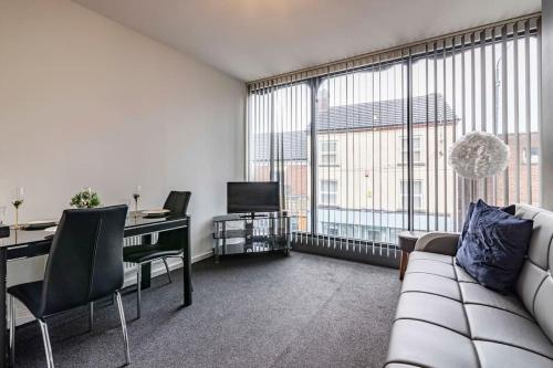 a living room with a couch and a desk with a television at Modern flat in Eastwood Town centre in Eastwood