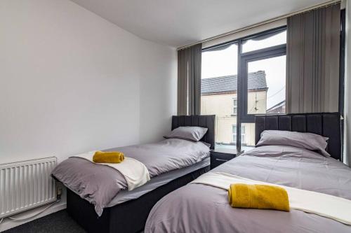 two beds in a room with a window at Modern flat in Eastwood Town centre in Eastwood