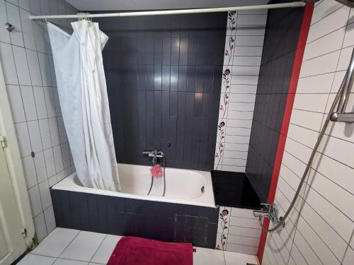 a bathroom with a bath tub with a shower curtain at Appartement standing Nabeul in Nabeul