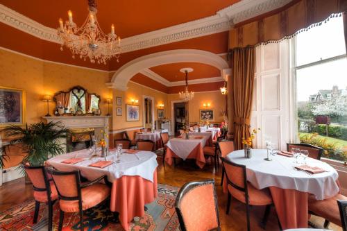 um restaurante com mesas e cadeiras e um lustre em Kildonan Lodge Hotel em Edimburgo
