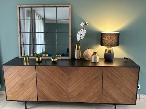 a dresser with a mirror and a lamp on it at L'escale du Trianon in Le Plessis-Robinson