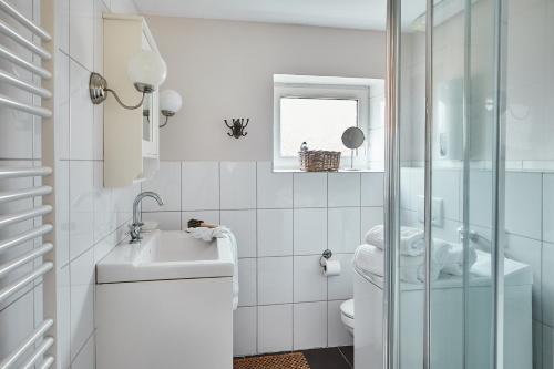 a white bathroom with a sink and a toilet at Gut Hohenstein - Stellmacherhaus in Barkelsby