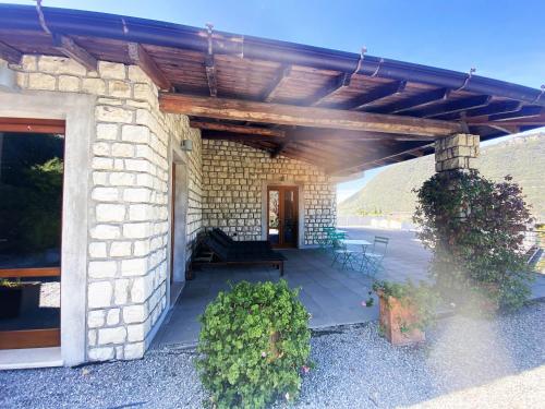 a stone house with a patio with a wooden roof at Vela di Soleville camere con e senza vista lago con ristorante & pizzeria in Sale Marasino