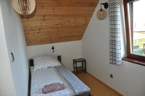 1 dormitorio con cama y techo de madera en BEY Domki całoroczne, en Sztutowo