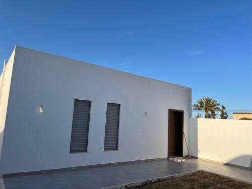 a white building with two windows on the side of it at Dar Malika in El Guecheïne