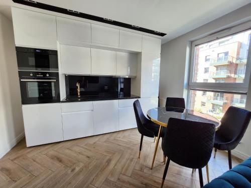 uma cozinha com armários brancos e uma mesa e cadeiras em Marina Apartments em Gdansk