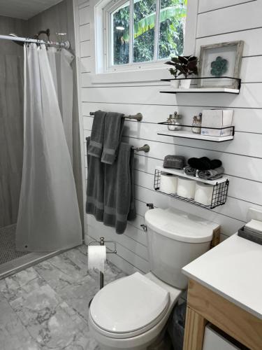 a white bathroom with a toilet and a shower at Maria's Farm House in Homestead