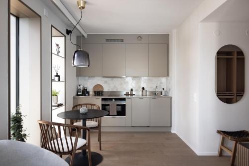cocina con armarios blancos, mesa y sillas en Norra Station Executive Suite - 3km from City Centre, en Estocolmo