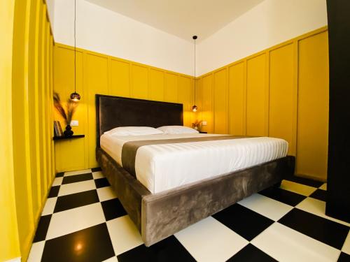 a bedroom with a bed with yellow walls and a checkered floor at PROMO Elegant Apartments NEW - Colorful by the sea in Durrës