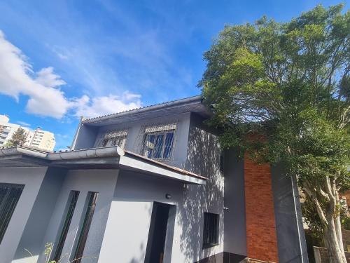 a white house with a tree in front of it at HOSTEL FAMILIA ZANATTA in Caxias do Sul