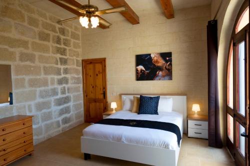 a bedroom with a bed and a stone wall at VillaNirvana in Qala