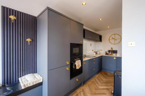 a kitchen with blue cabinets and a clock on the wall at Priory Bay Escapes - Matahari in Tenby