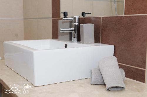 a white sink in a bathroom with a towel at Baltic Zen - Apartament in Hel
