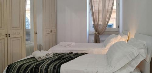 - 2 lits blancs dans une chambre avec un miroir dans l'établissement Appartamento storico in zona Barberini, à Rome