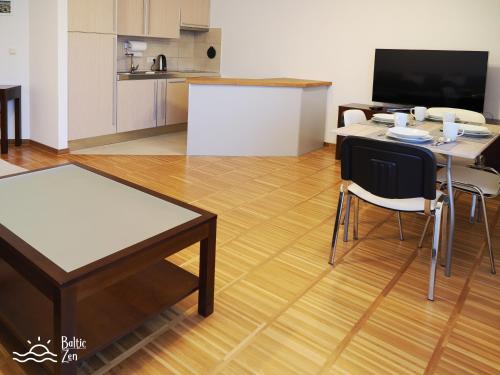 een woonkamer met een tafel en stoelen en een keuken bij Baltic Zen - Apartament in Hel