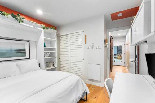 a white bedroom with a large white bed and an orange wall at Modern Sustainable Design in Ballard - 92 Wlkscore in Seattle