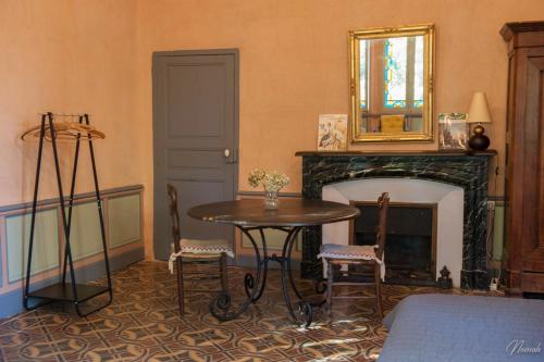 Cette chambre dispose d'une table et d'une cheminée avec un miroir. dans l'établissement Gîte du parc à Langel, à Armissan