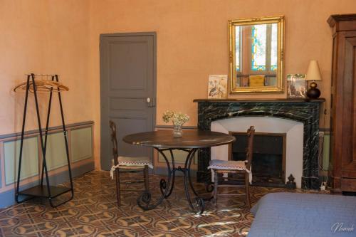a room with a table and a fireplace with a mirror at Gîte du parc à Langel in Armissan