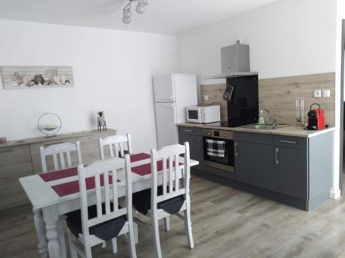 uma cozinha com uma mesa e cadeiras, um fogão e um frigorífico em Mini villa 84 sur la route des vins em Sainte-Cécile-les-Vignes